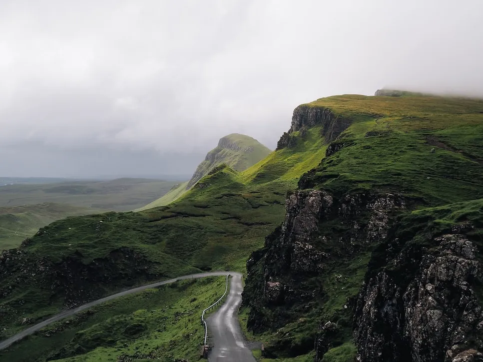 Picturesque country road with lush greenery juxtaposed with a gloomy sky.